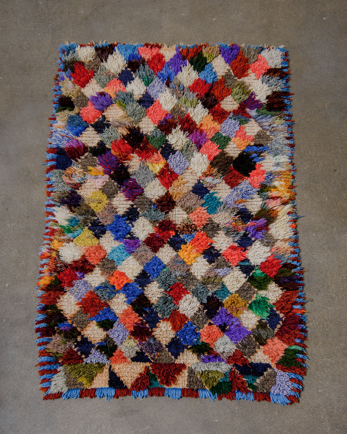 Multicoloured textured rug on a grey surface